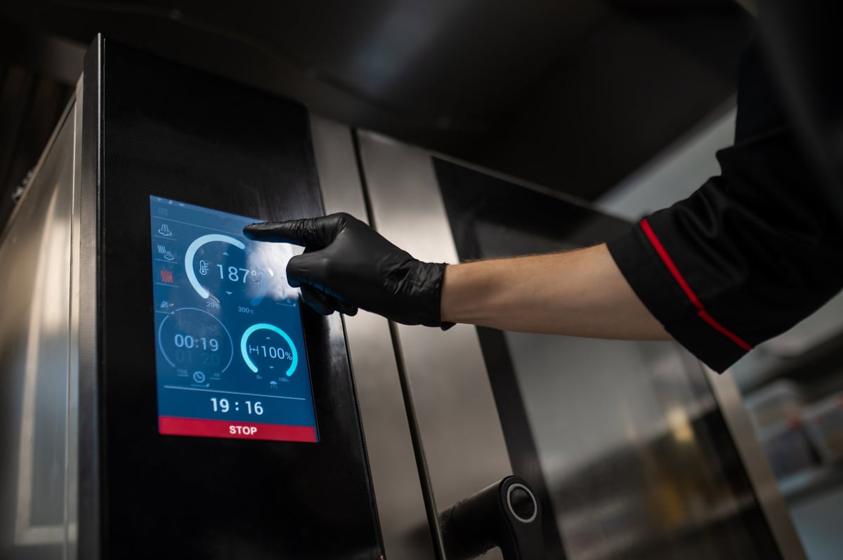 Operador usando equipo de cocina industrial en acero inoxidable